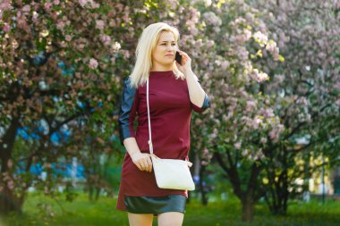 bahar çiçek açan parkta smartphone kullanarak sarışın genç kadın portresi