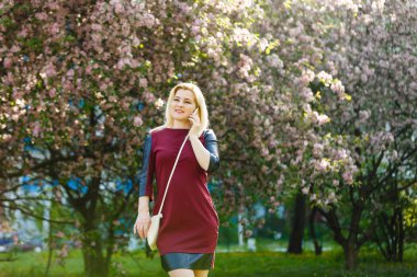 bahar çiçek açan parkta smartphone kullanarak sarışın genç kadın portresi