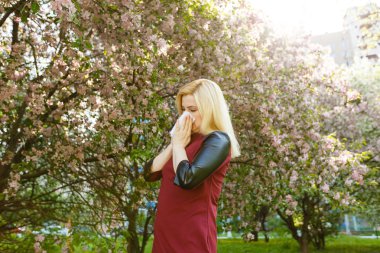 Genç kadın çiçek açan ağaç önünde burun üfleme