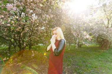 Genç kadın çiçek açan ağaç önünde burun üfleme