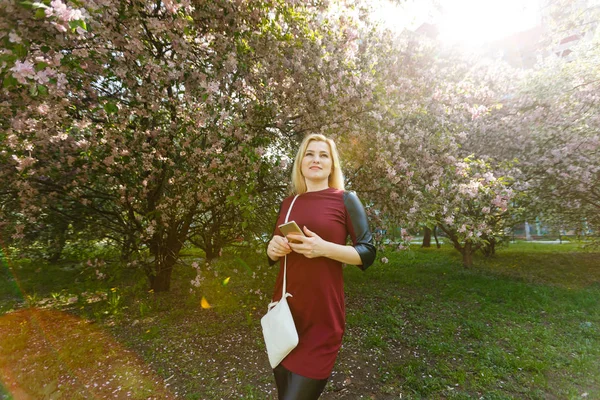 Porträtt Unga Blonda Kvinnan Använda Smartphone Våren Blommande Park — Stockfoto