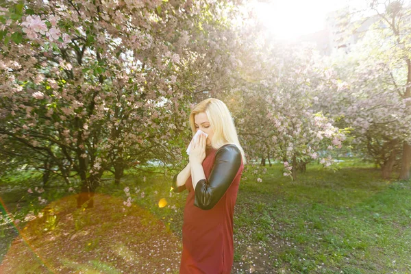 Ung Kvinna Blåser Näsan Framför Blommande Träd — Stockfoto