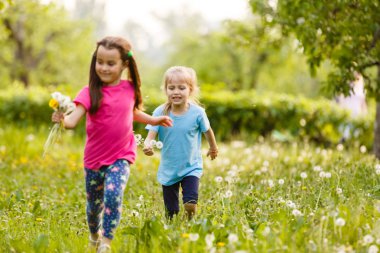 Dandelions alanıyla üzerinde yürüyen iki mutlu küçük kız