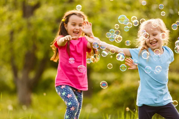 Дві Дівчини Задоволені Плавучими Мильними Бульбашками Зеленому Парку Заході Сонця — стокове фото