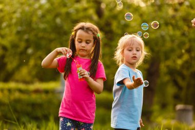 Yeşil parkta oynarken ve kayan sabun köpüğü üfleme iki kız