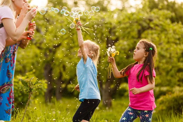 两个女孩在绿色公园玩耍 吹漂浮的肥皂泡 — 图库照片