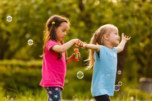 Dvě Dívky Hrát Zeleném Parku Foukání Plovoucí Mýdlové Bubliny — Stock fotografie
