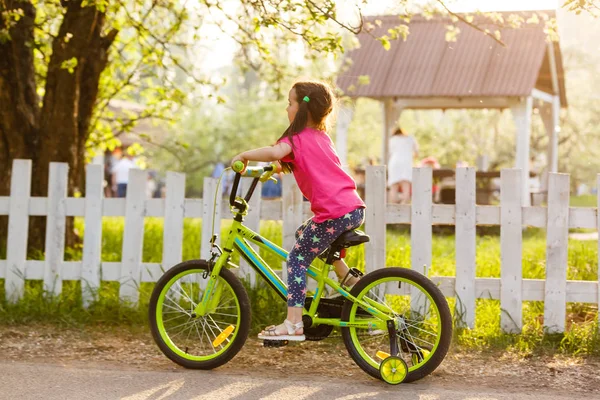 Little girl riding bicycle in countryside at sunset