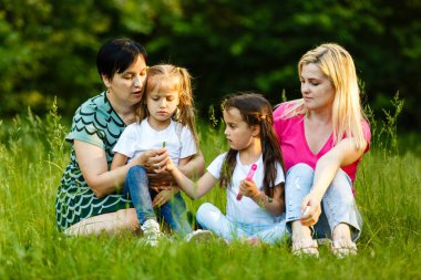 Yeşil parkta dinlenmiş okul öncesi kızları olan iki anne