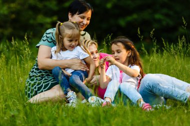 Yeşil parkta dinlenmiş okul öncesi kızları olan iki anne