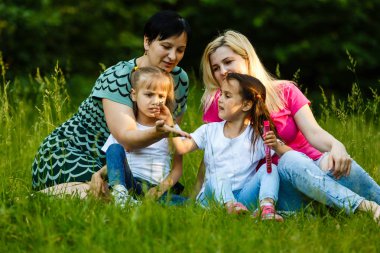 Yeşil parkta dinlenmiş okul öncesi kızları olan iki anne