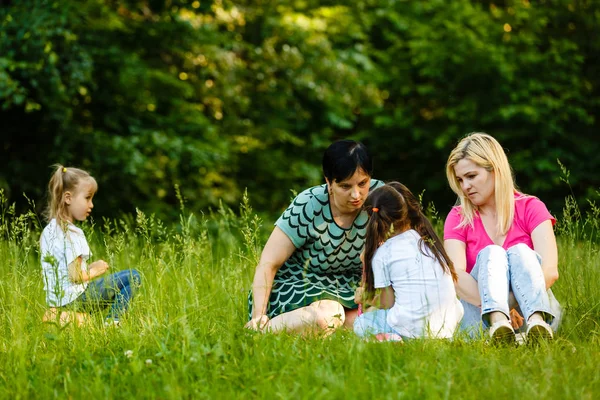 緑の公園で休んでいる就学前の娘を持つ2人の母親 — ストック写真