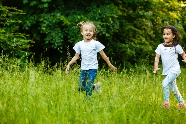 Happy children running in green summer park