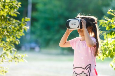 Sanal gerçeklik kulaklık üzerinde arka bahçesinde oynayan kızla  