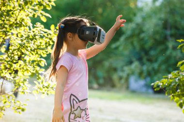 Sanal gerçeklik kulaklık üzerinde arka bahçesinde oynayan kızla  