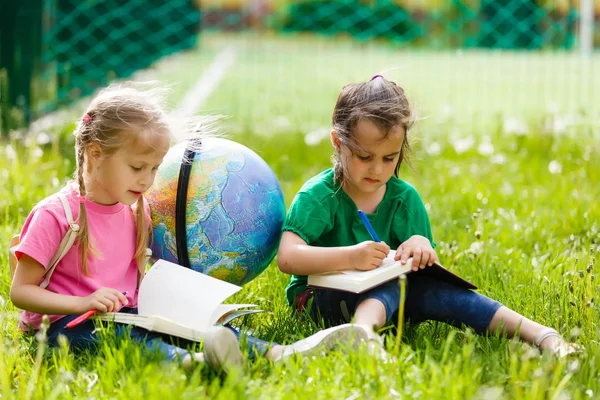 Zwei Kleine Schulmädchen Sitzen Auf Gras Mit Globus — Stockfoto