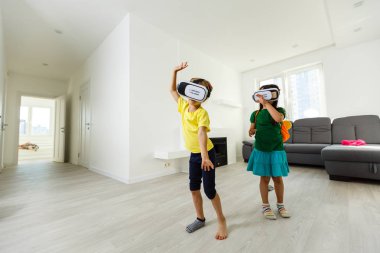 iki küçük kız sanal kullanarak gerçeklik evde oturma odasında gözlükler.