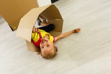 Küçük kız modern oturma odasında kağıt kutuları ile oynuyor 