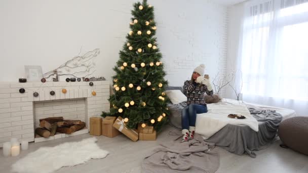 年轻女子使用智能手机和休息在圣诞节装饰的房间 — 图库视频影像