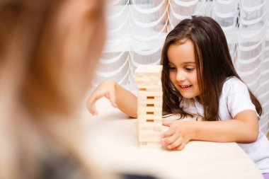 Evde ahşap bloklar ile oynayan küçük esmer kız 