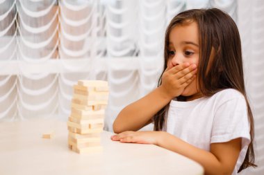 Evde ahşap bloklar ile oynayan küçük esmer kız 