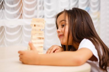 Evde ahşap bloklar ile oynayan küçük esmer kız 