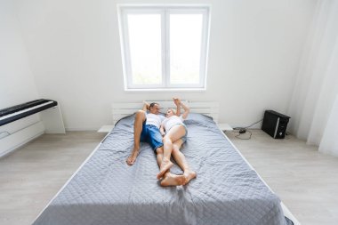 Genç mutlu çift yatarken aşağı üzerinde yatak içinde yeni ışık yatak odası 