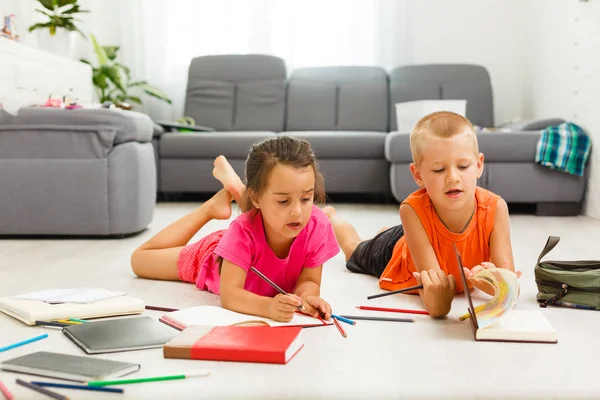 little girl with boy of preschool age studding at home on floor