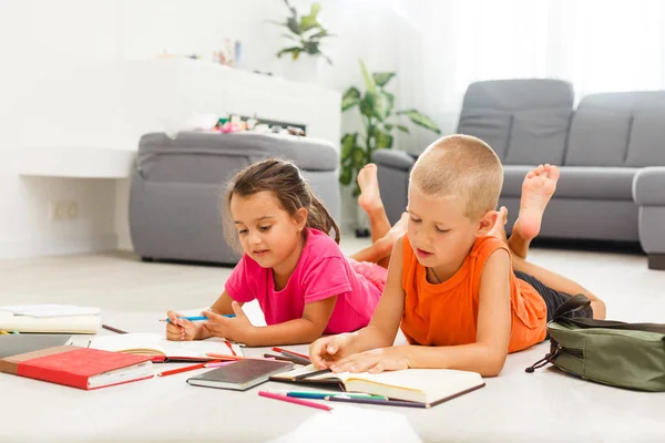 little girl with boy of preschool age studding at home on floor