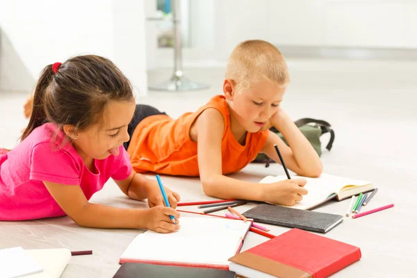 little girl with boy of preschool age studding at home on floor