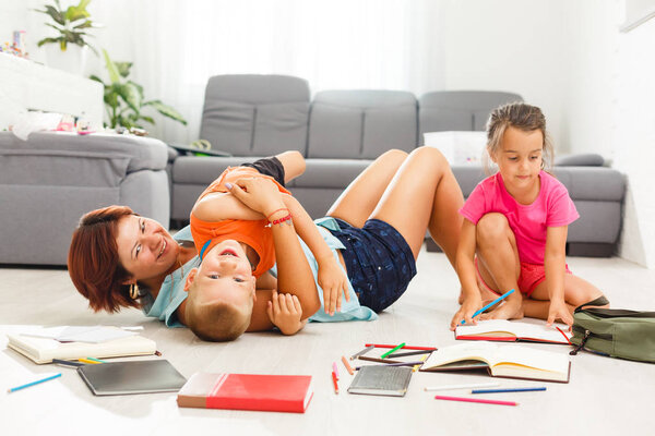 счастливая семья с двумя детьми, играющими на полу в гостиной
