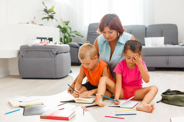 счастливая семья с двумя детьми, играющими на полу в гостиной
