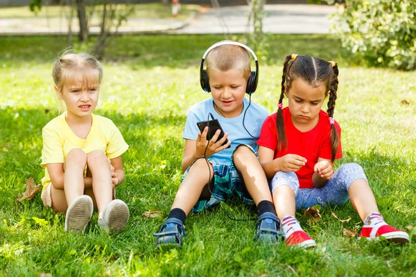 Gesellschaft Von Kindern Die Mit Smartphone Park Auf Gras Sitzen — Stockfoto