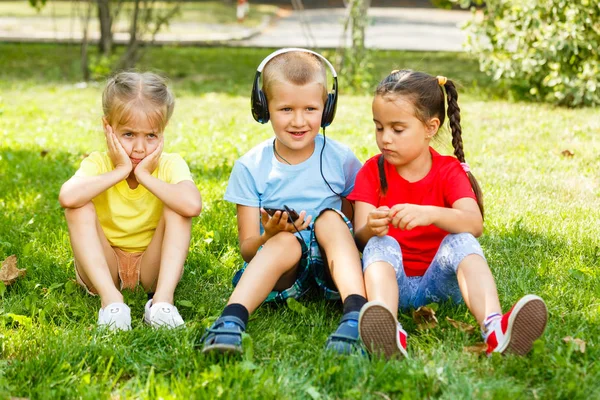 Gesellschaft Von Kindern Die Mit Smartphone Park Auf Gras Sitzen — Stockfoto