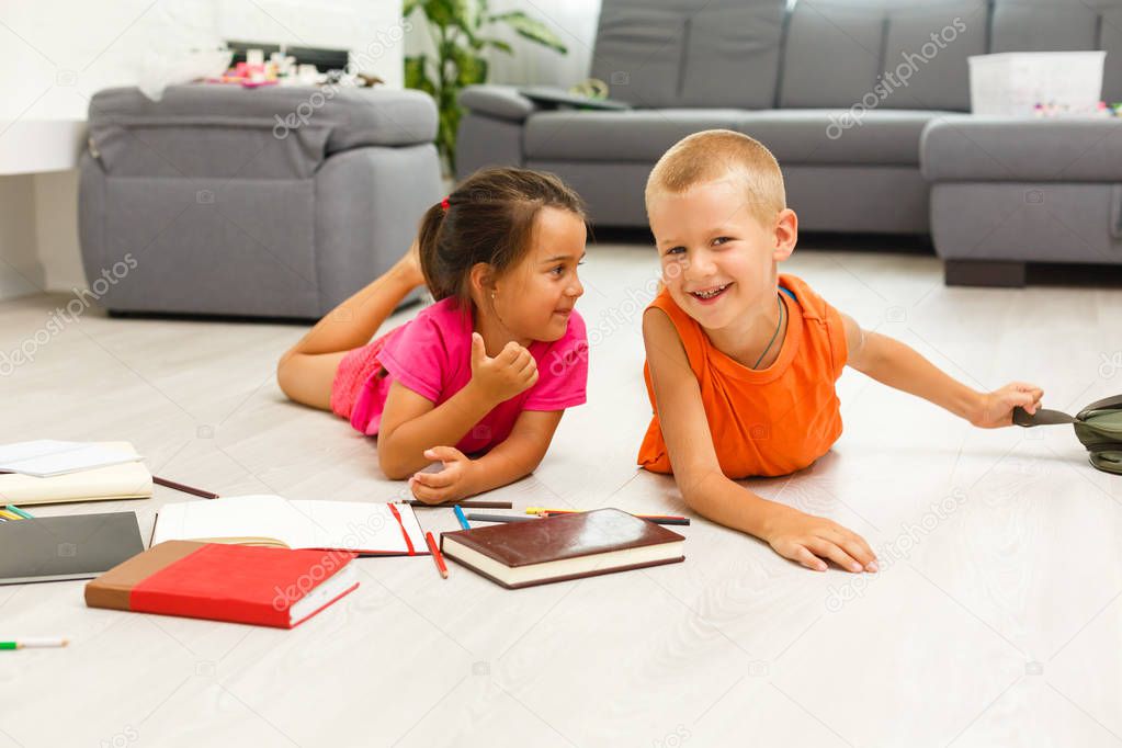 little girl with boy of preschool age studding at home on floor 