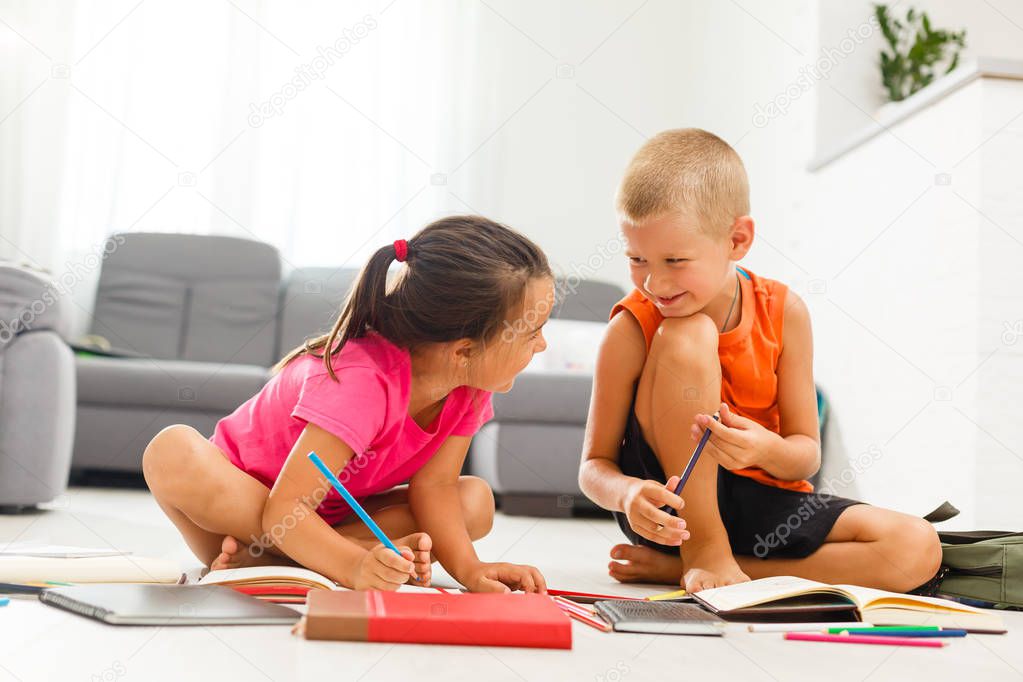 little girl with boy of preschool age studding at home on floor 