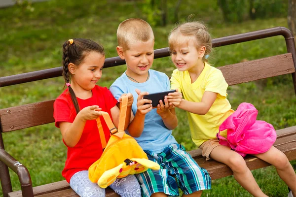 Tres Niños Felices Jugando Con Teléfono Inteligente Banco Parque —  Fotos de Stock