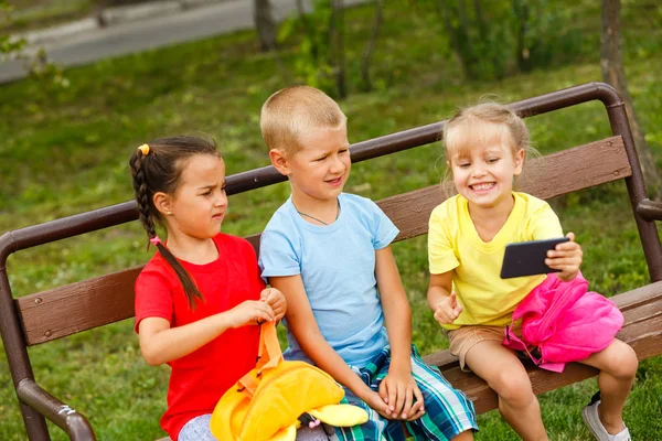 Tři Šťastné Děti Hrají Smartphone Lavičce Parku — Stock fotografie