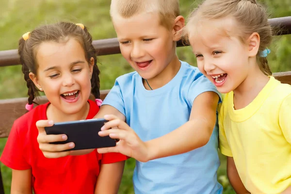 Drie Gelukkige Kinderen Spelen Met Smartphone Bankje Park — Stockfoto