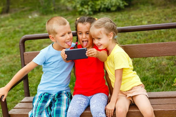 Tres Niños Felices Jugando Con Teléfono Inteligente Banco Parque —  Fotos de Stock