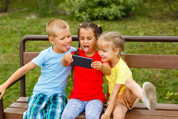 Tres Niños Felices Jugando Con Teléfono Inteligente Banco Parque — Foto de Stock