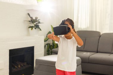 evde oturma odasında sanal gerçeklik gözlüğü kullanarak küçük kız