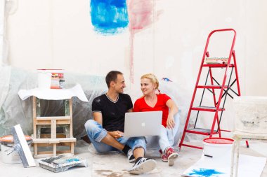 Daire onarım yapıyor ve dizüstü bilgisayar kullanarak genç çift