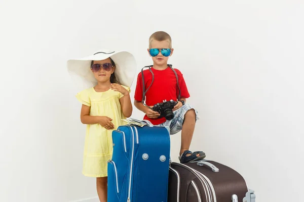 Brother and sister with travel luggage posing on white background