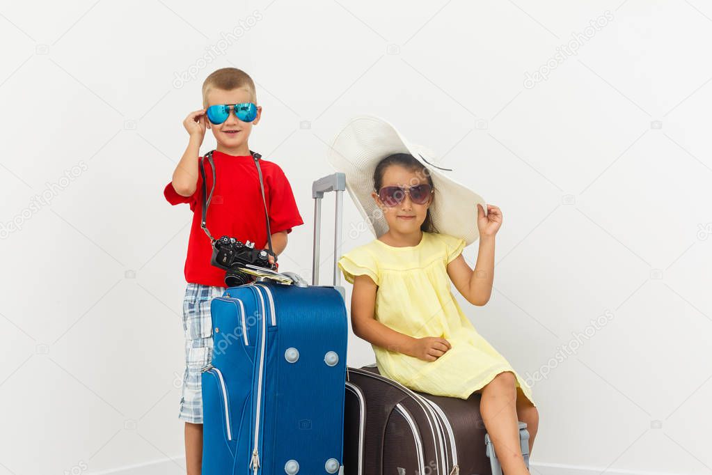 Brother and sister with travel luggage posing on white background 