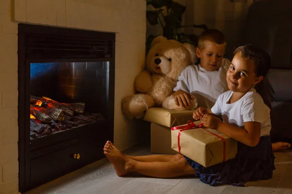 Kleine Mädchen Und Jungen Sitzen Mit Geschenken Vor Dem Kamin — Stockfoto