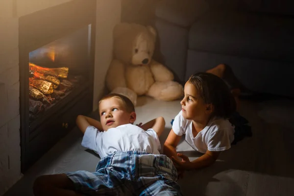 Mädchen Und Junge Sitzen Mit Koffer Vor Kamin — Stockfoto