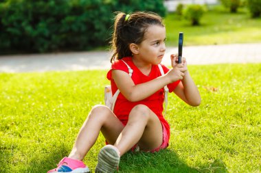 yeşil parkta büyüteç ile oynayan küçük kız