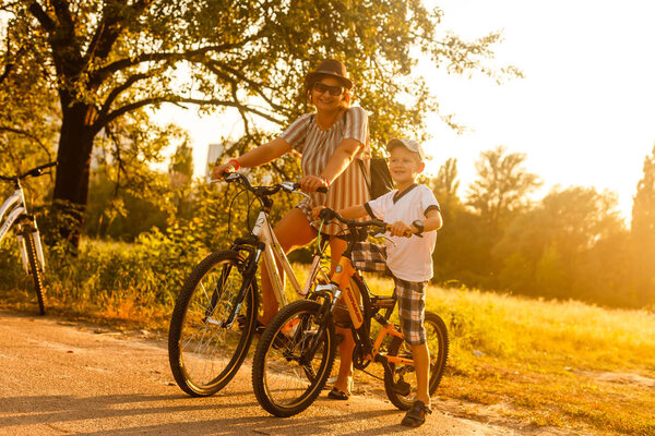 Happy woman with son riding bikes at sunset