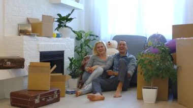 Genç çift gülüyor ve evde şömine yakın katta otururken kameraya bakıyor